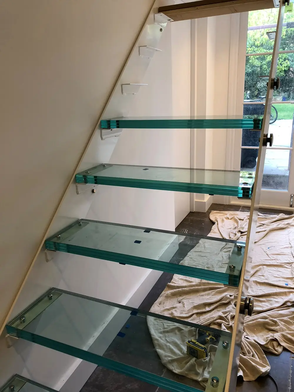 A glass staircase, with the glass steps carried on steel beams up each side